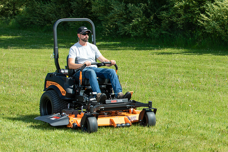 A man operating a Scag Tiger Cat II in a grassy field.